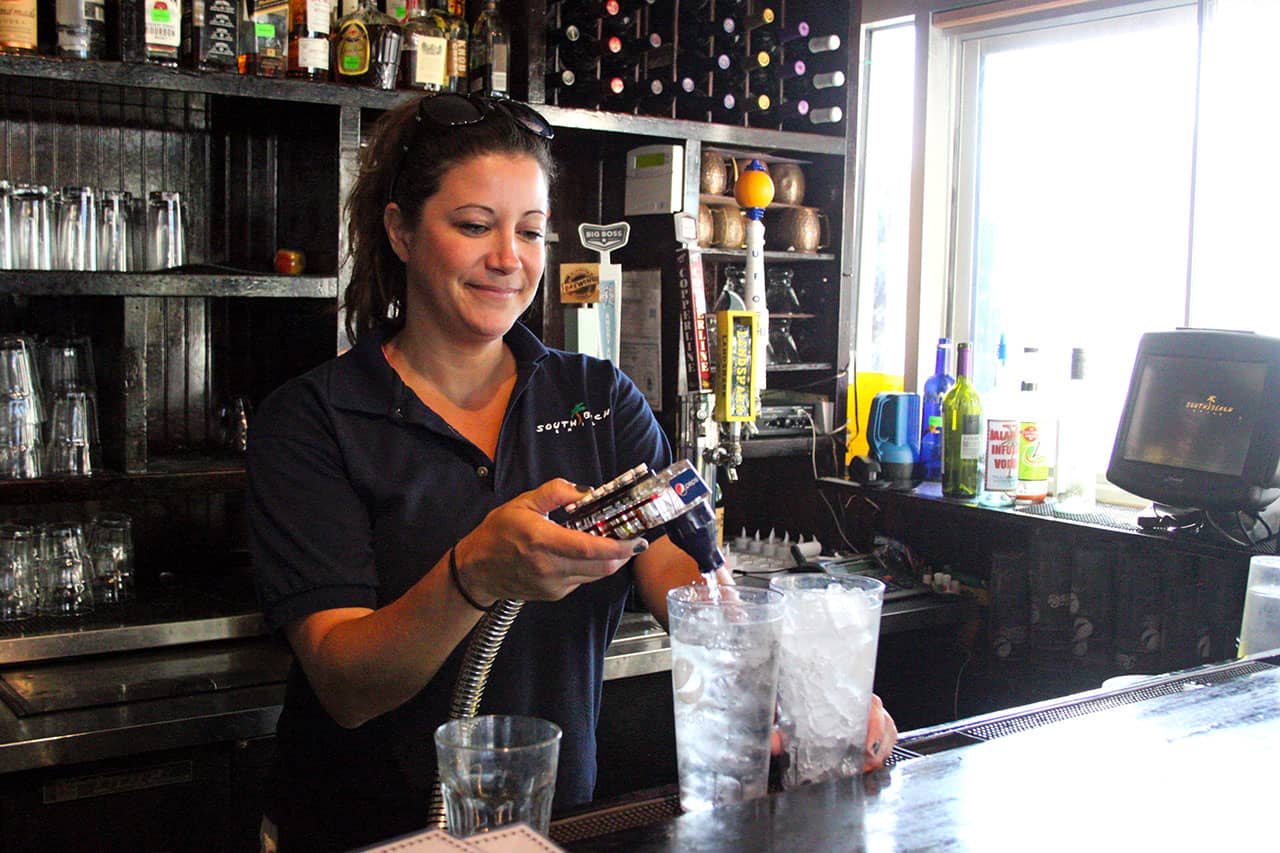 Bar tender pouring glasses of water and on tap craft beer at South Beach Grill